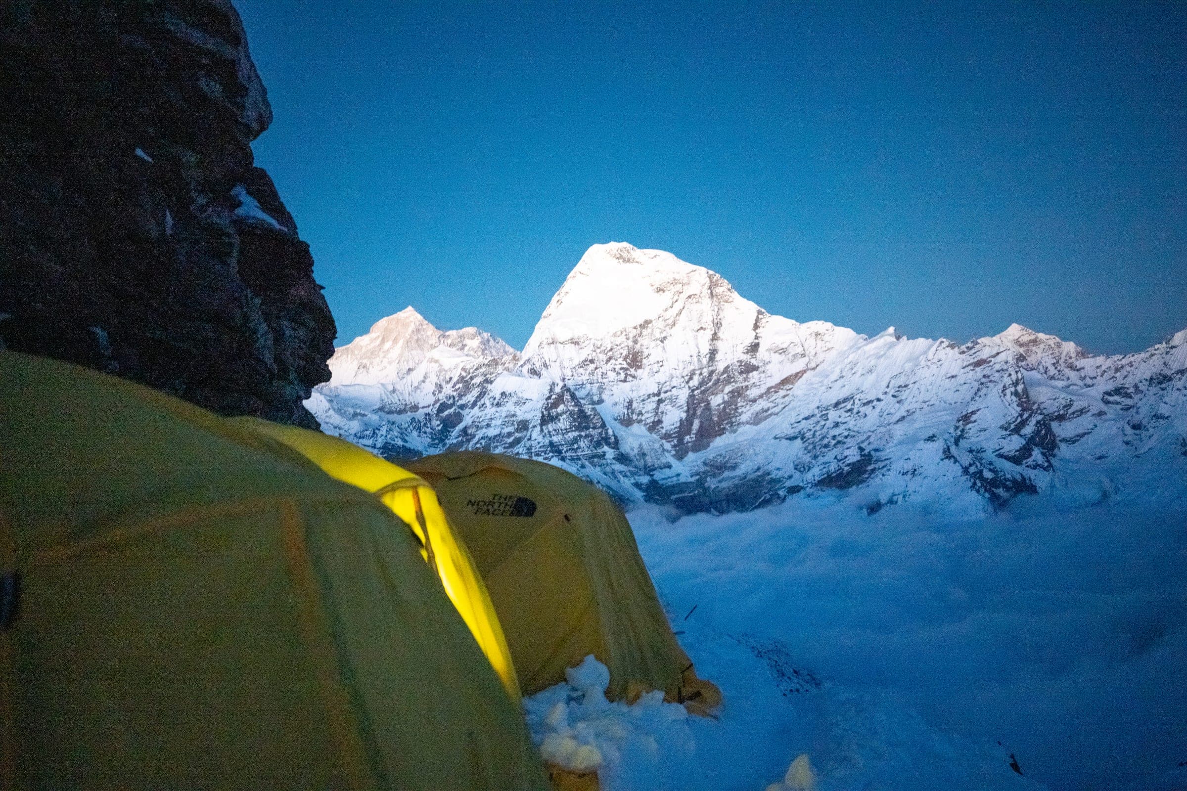 Yellow expedition tents on a snow ridge above the clouds, Mera Peak high camp